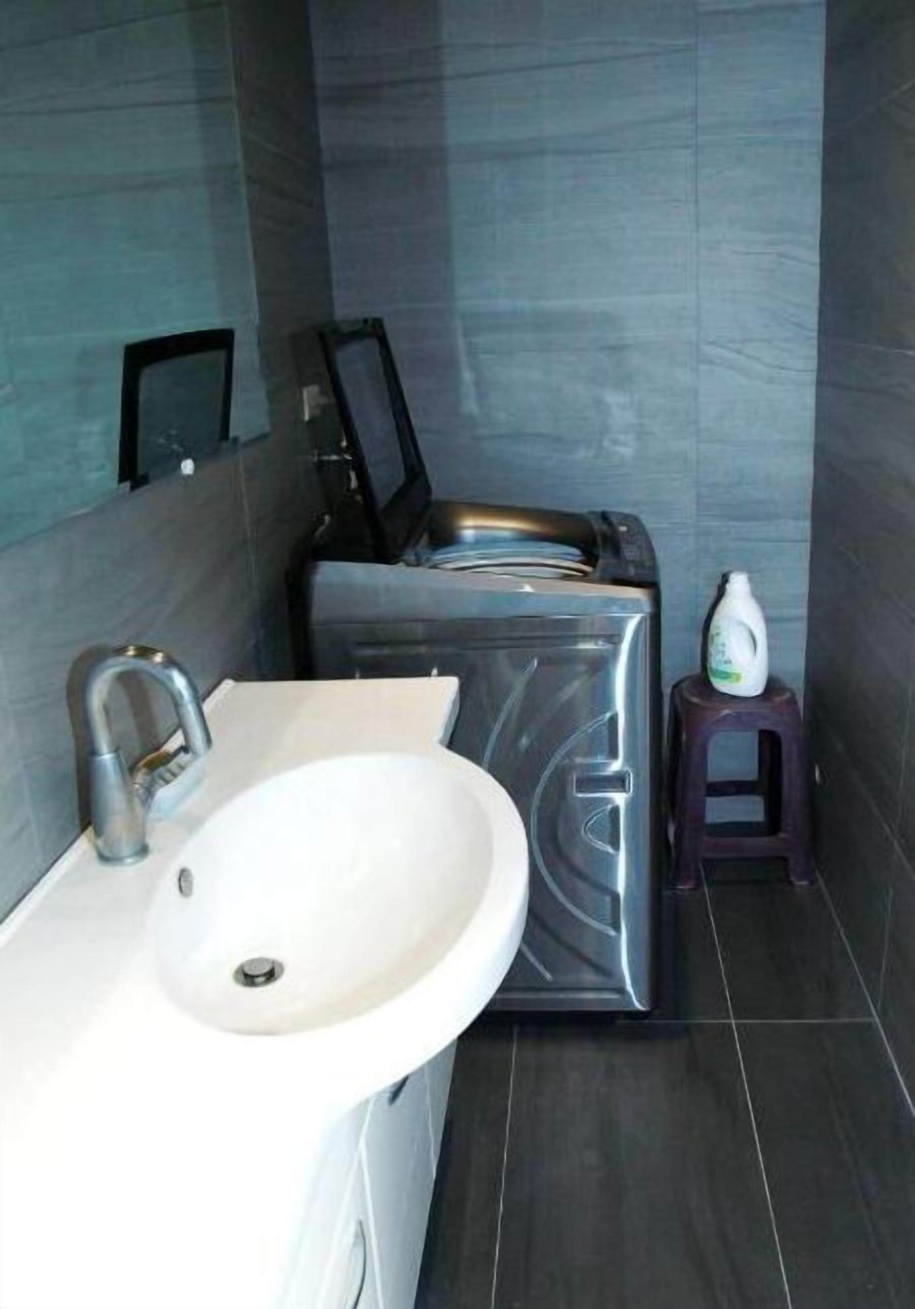 Un baño con lavabo, espejo y lavadora-secadora compacta.