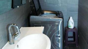 Un baño con lavabo, espejo y lavadora-secadora compacta.