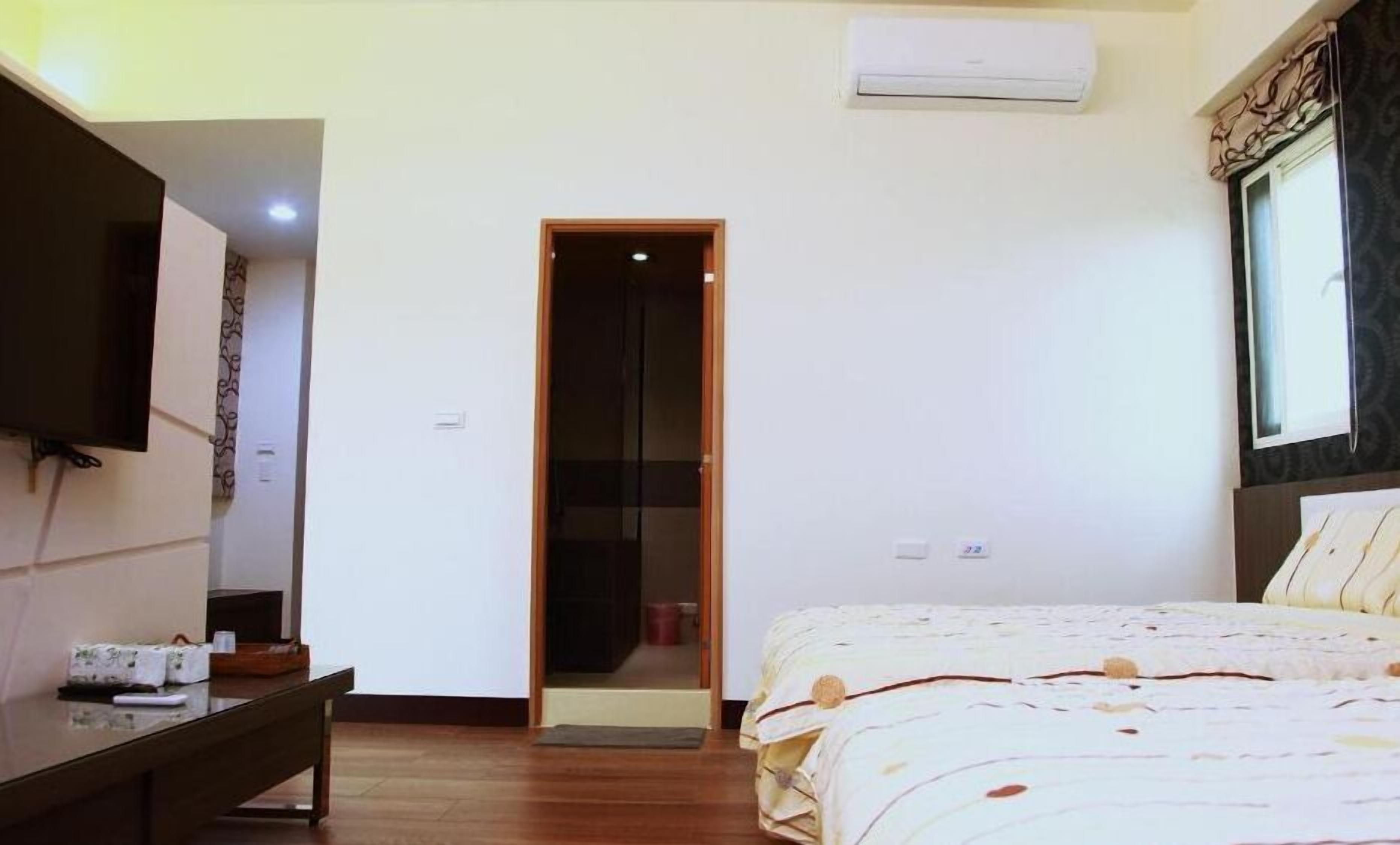 Quarto com cama, escrivaninha, televisão e ar condicionado.
