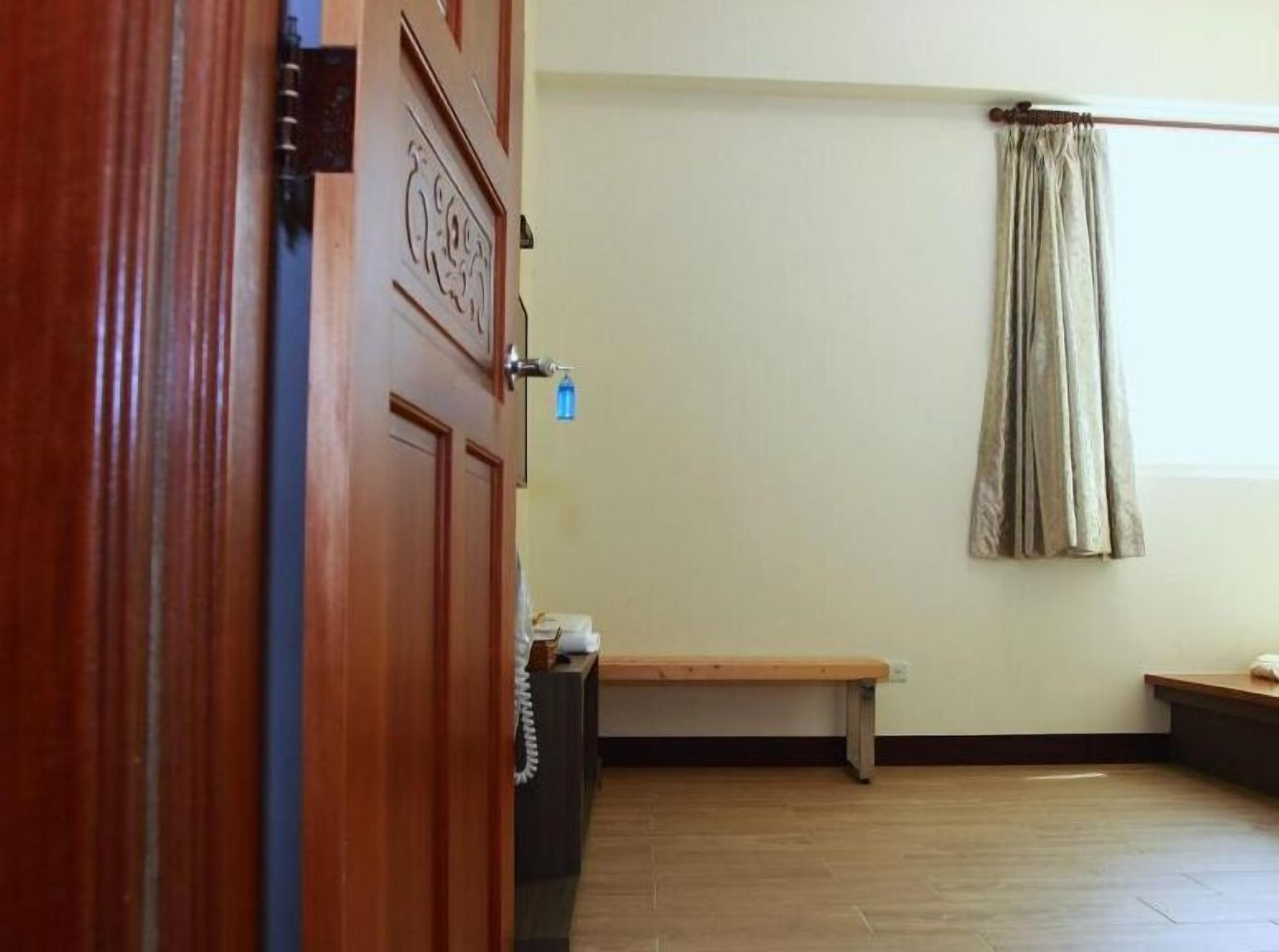 A room with a wooden door, a bench, a curtain, and a wall-mounted light fixture.