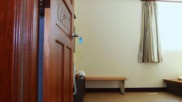 A room with a wooden door, a bench, a curtain, and a wall-mounted light fixture.