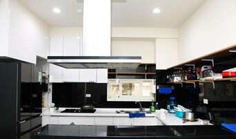 Una cocina moderna con armarios blancos, encimera negra y campana extractora de acero inoxidable.