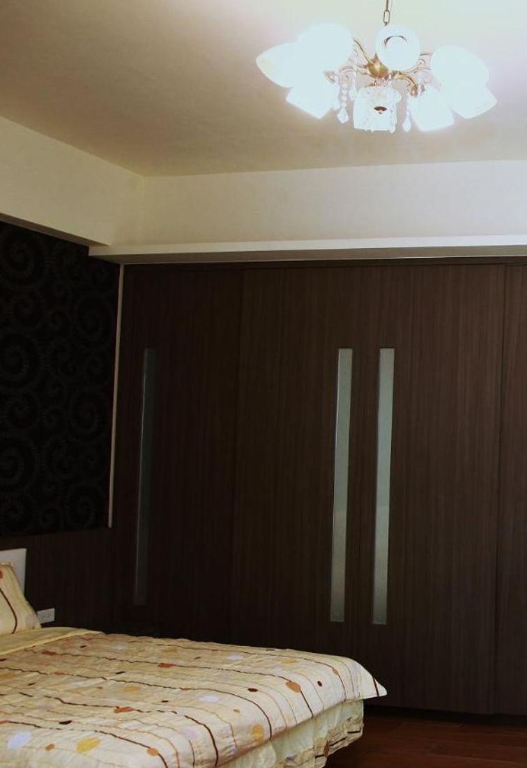 Un dormitorio con una cama, un armario de madera oscura y un candelabro.