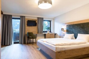 A modern hotel room with a large bed, a desk, and a television. - Hotel Bergland Obsteig (Obsteig)