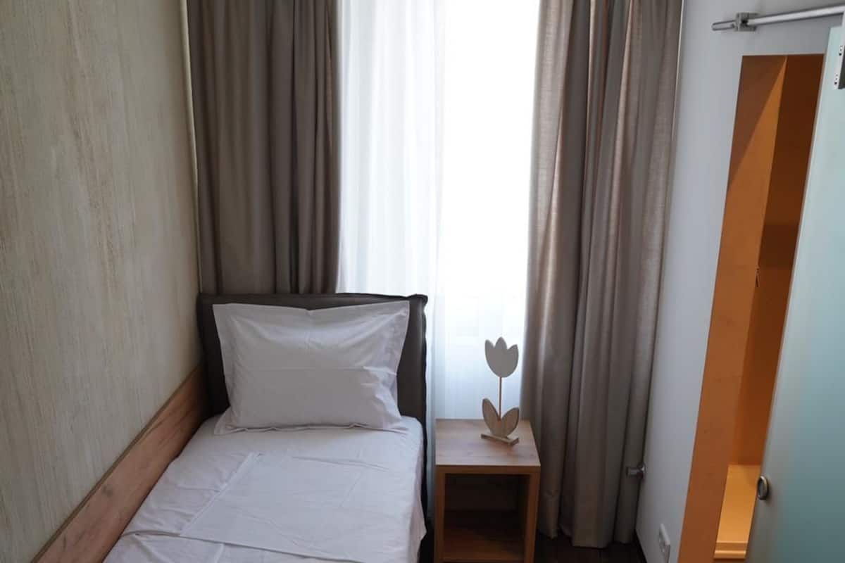 Habitación de hotel con cama, mesita de noche, una pequeña mesa con un adorno y vistas al exterior a través de la ventana.