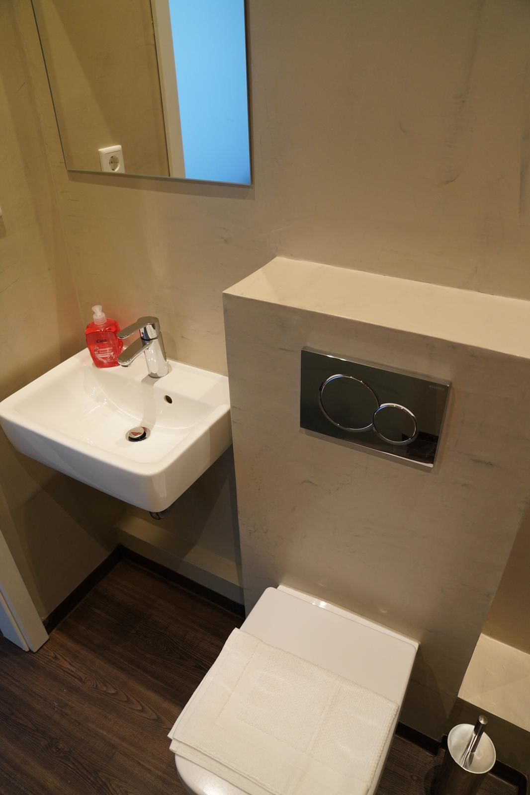 Ein Badezimmer mit weißem Waschbecken, Spiegel, Toilette und Handtuchhalter.