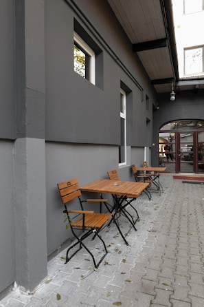 An outdoor seating area with tables and benches against a building facade. - Meteor Central (Cluj-Napoca)