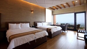 Habitación de hotel con dos camas, un balcón con vistas al mar y un ventanal grande.