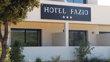 Un bâtiment moderne avec une enseigne indiquant « HÔTEL FAZIO » et affichant trois étoiles.