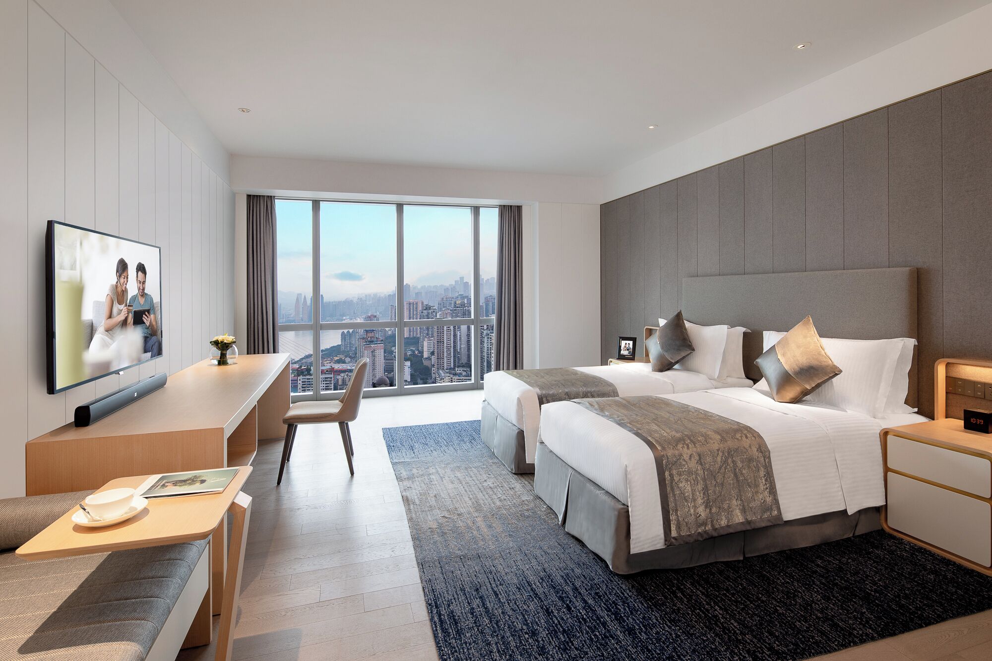 Une chambre d’hôtel moderne dotée d’une grande fenêtre, d’un lit, d’un bureau et d’un téléviseur.