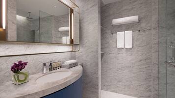 Un baño moderno con encimera de mármol, un espejo grande y una cabina de ducha de vidrio.