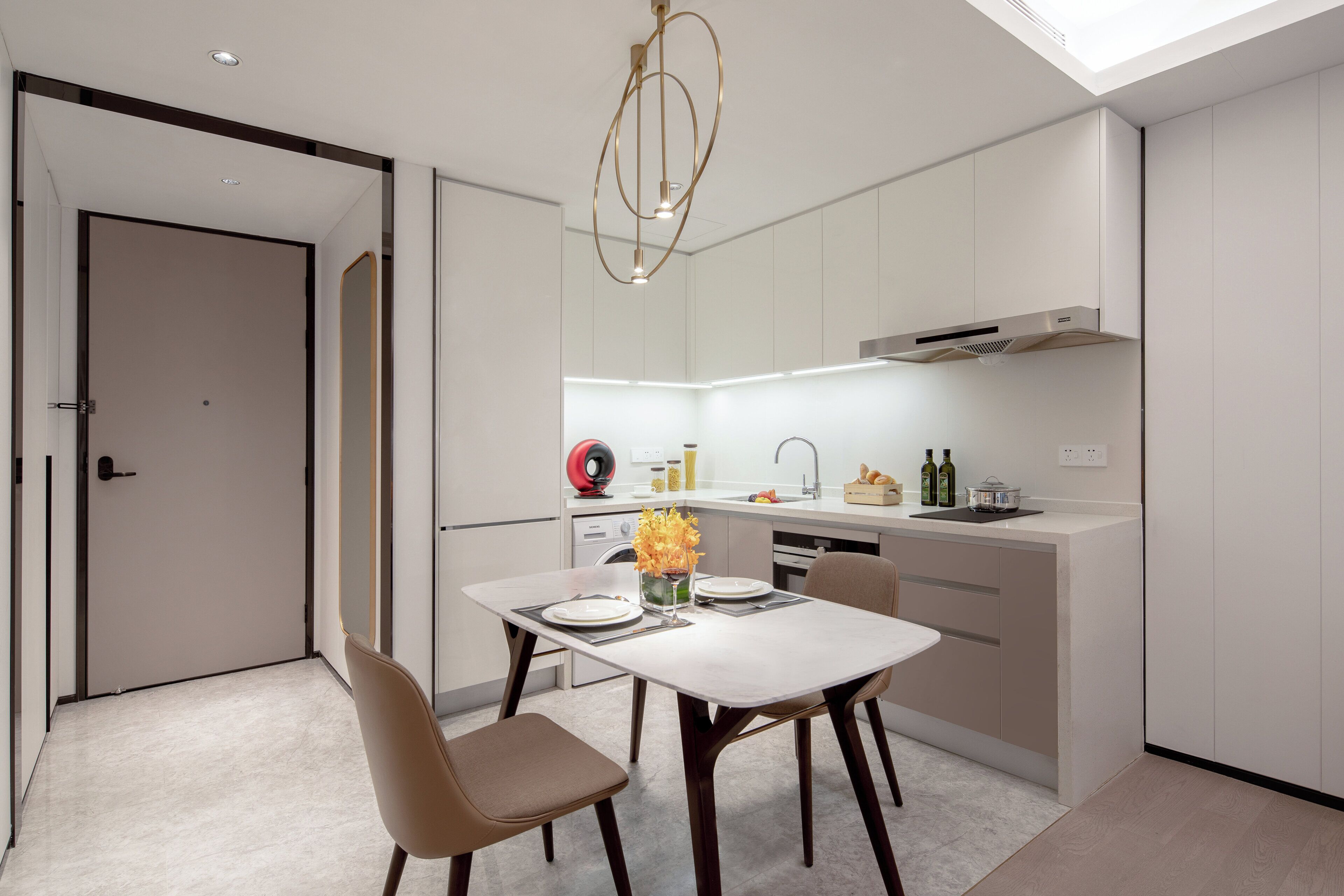 Una cocina moderna con zona de comedor, que incluye un horno empotrado, un fregadero y una isla compacta con campana extractora.