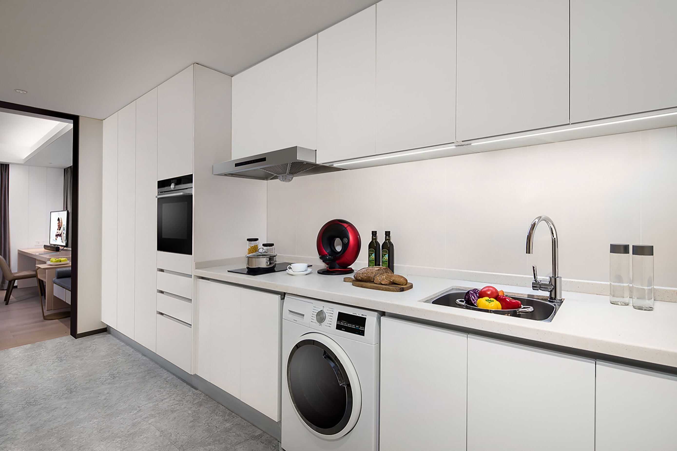 Une cuisine moderne équipée d’un lave-linge intégré, d’un évier et d’un coin repas avec une chaise.