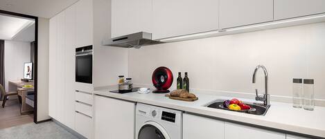 Une cuisine moderne équipée d’un lave-linge intégré, d’un évier et d’un coin repas avec une chaise.