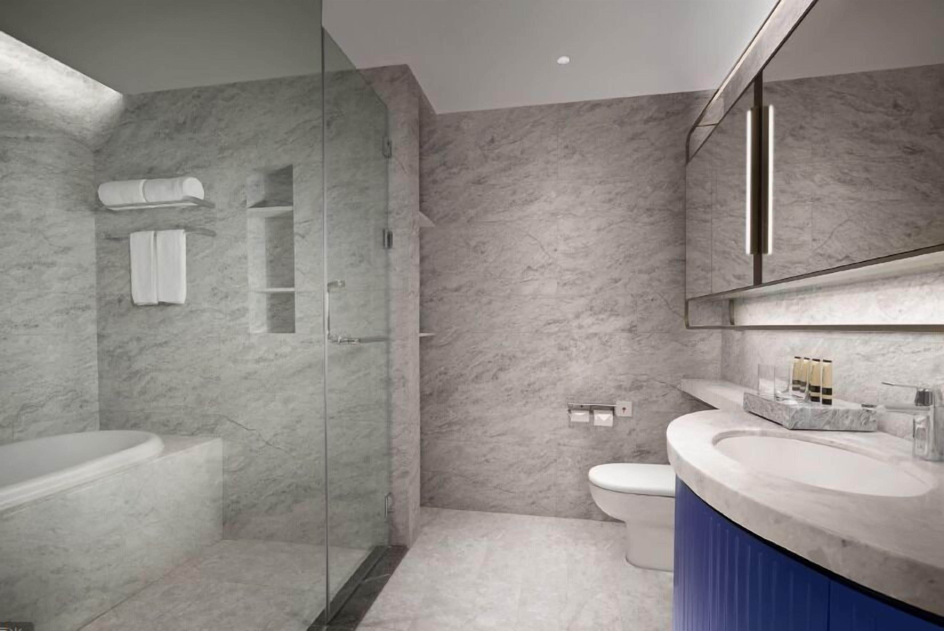 A modern bathroom with a glass-enclosed shower, a standalone bathtub, and a vanity with a sink and mirror.