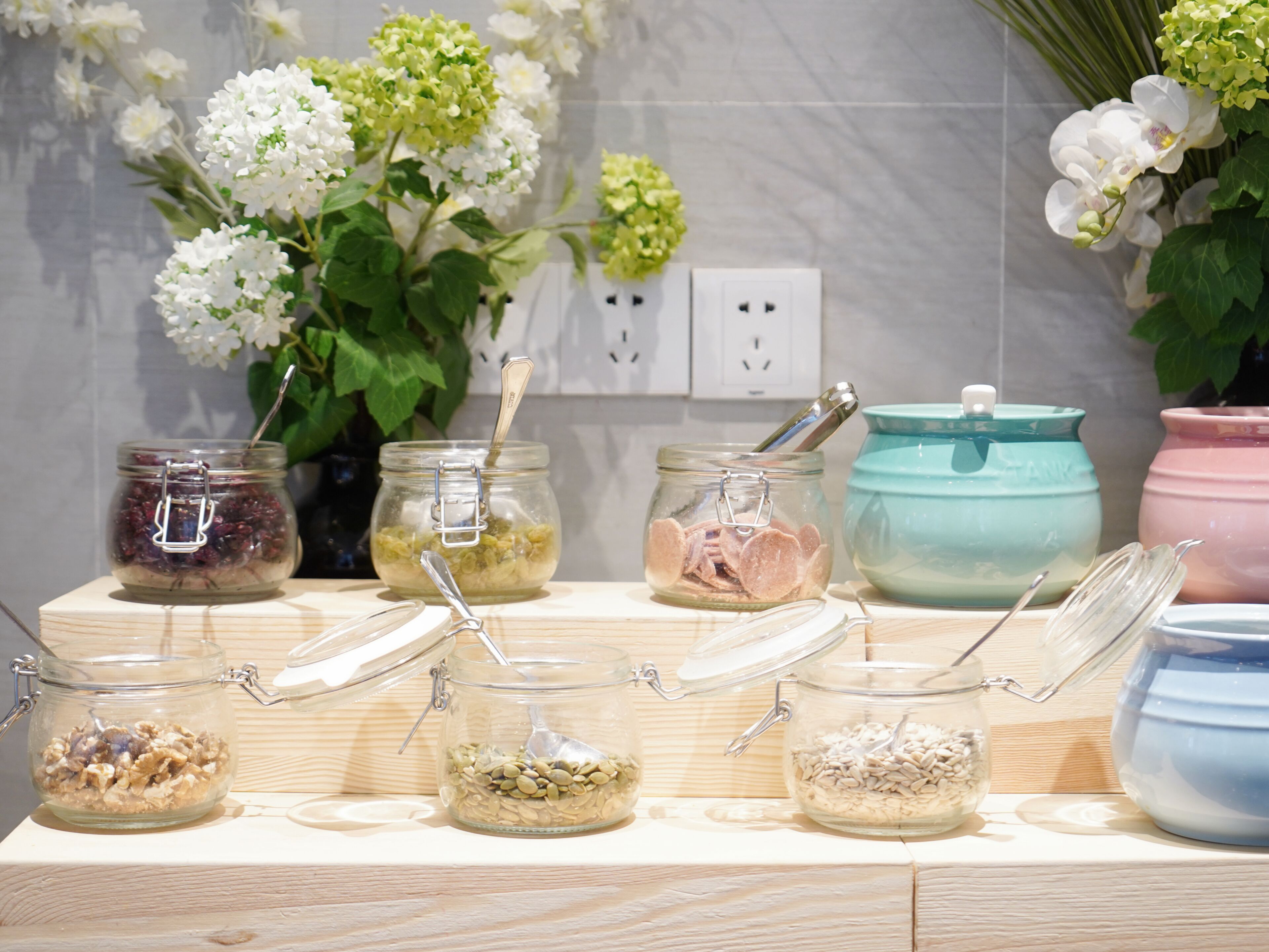 A kitchen counter with various food storage jars and a teal pot.