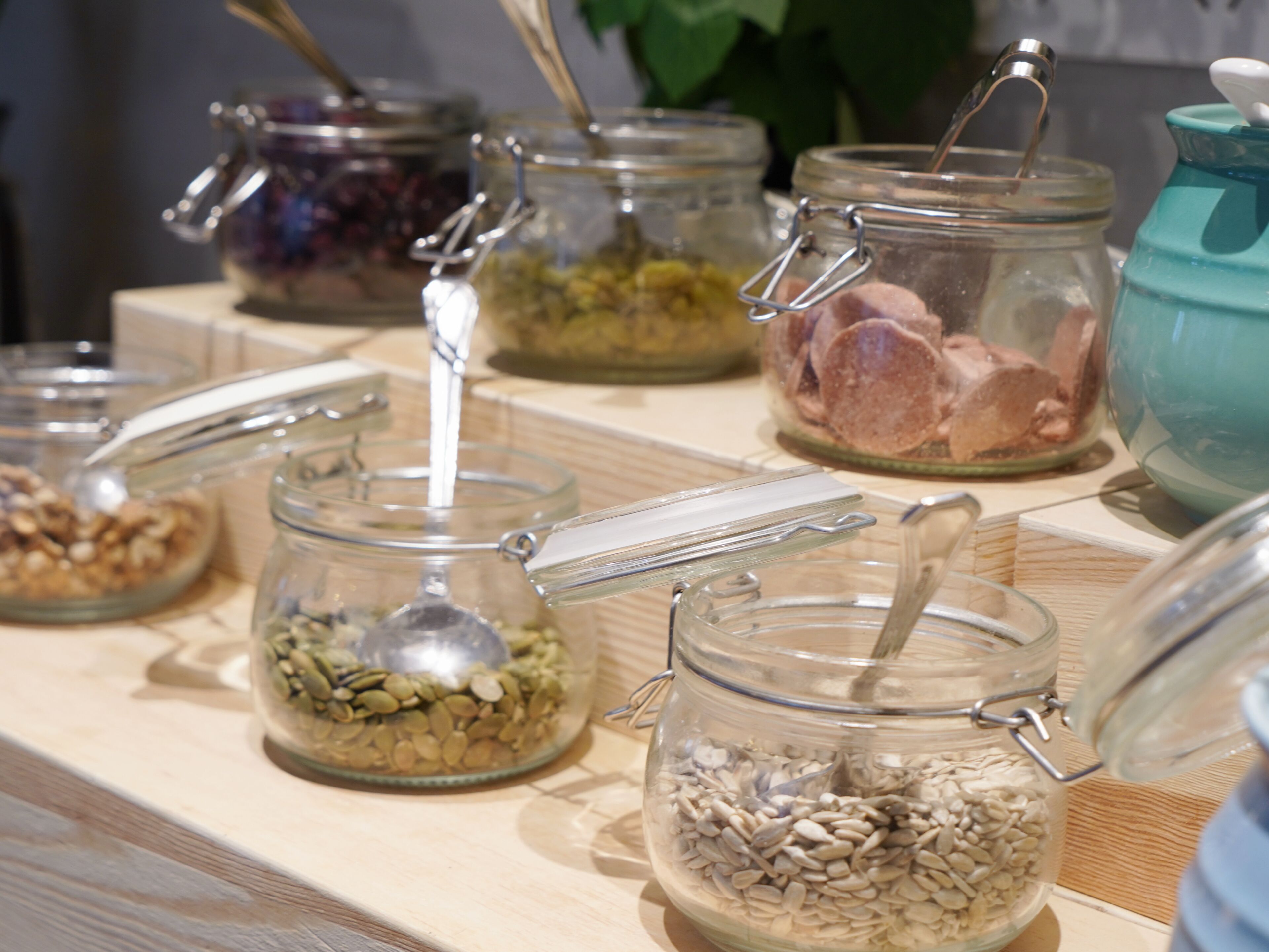 Diversos frascos de vidrio con cierres metálicos que contienen diferentes alimentos sobre una superficie de madera.