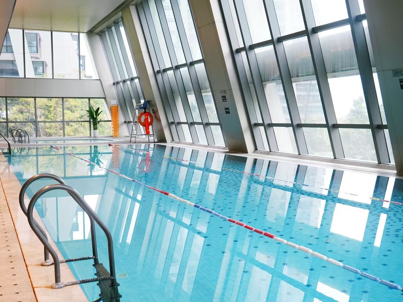 An indoor swimming pool with clear lanes, a lifeguard chair, and large windows.