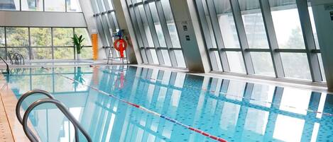 An indoor swimming pool with clear lanes, a lifeguard chair, and large windows.