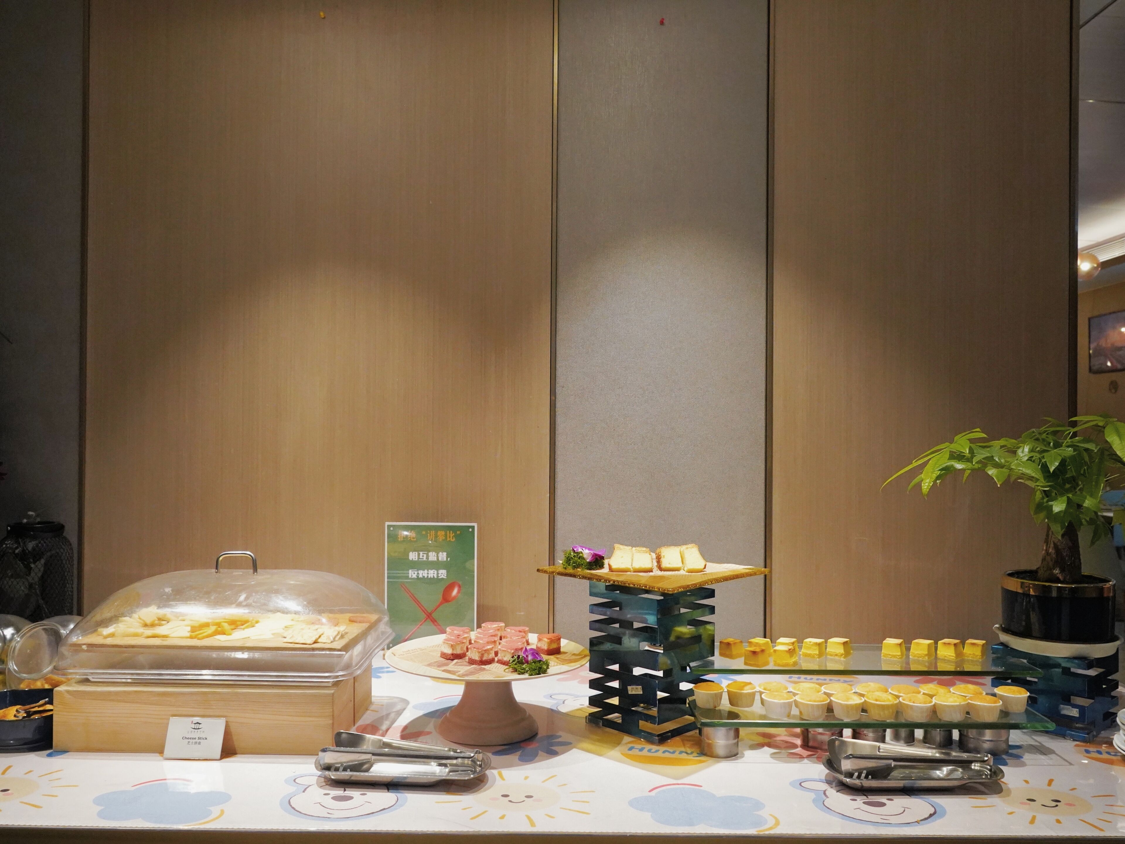 En buffet med forskellige spiser, heriblandt cheesesticks, desserter og en plante.