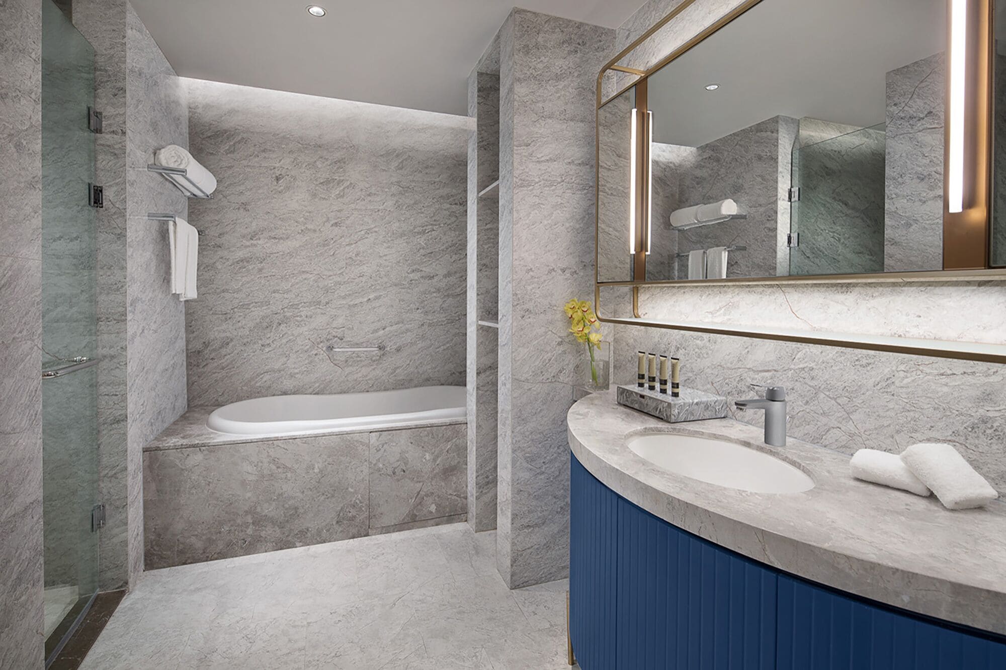 A modern bathroom with a bathtub, a shower, and a vanity with a mirror.