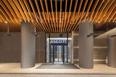 A modern entrance with a wooden slatted ceiling, a glass door entrance, and a sign reading 'ASCOTT.'. Ascott Raffles City Chongqing