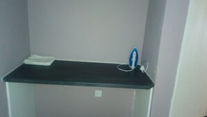 A small black shelf with a white cloth and a blue and white iron. - Ranks Guesthouse (Molepolole)