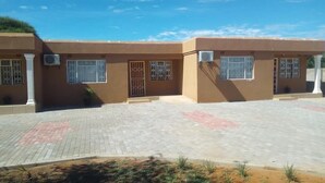 A building with a paved entrance area, columns, and barred windows. - Ranks Guesthouse (Molepolole)