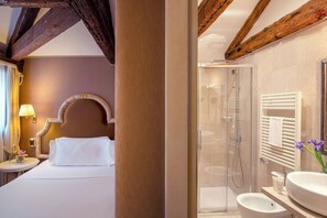 A hotel room with a bed, a bedside lamp, a mirror, a shower, and a sink. - Residenza Venezia | UNA Esperienze (Venice)