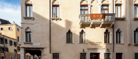 A historic building with arched windows and a balcony, labeled 'MAISON VENEZIA.'