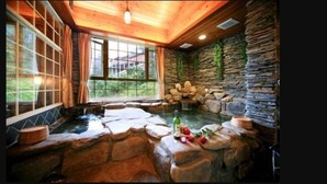 A spa area with a hot tub surrounded by stone walls and a wooden ceiling. - Ming Lu Holiday Hotel (Ren'ai)