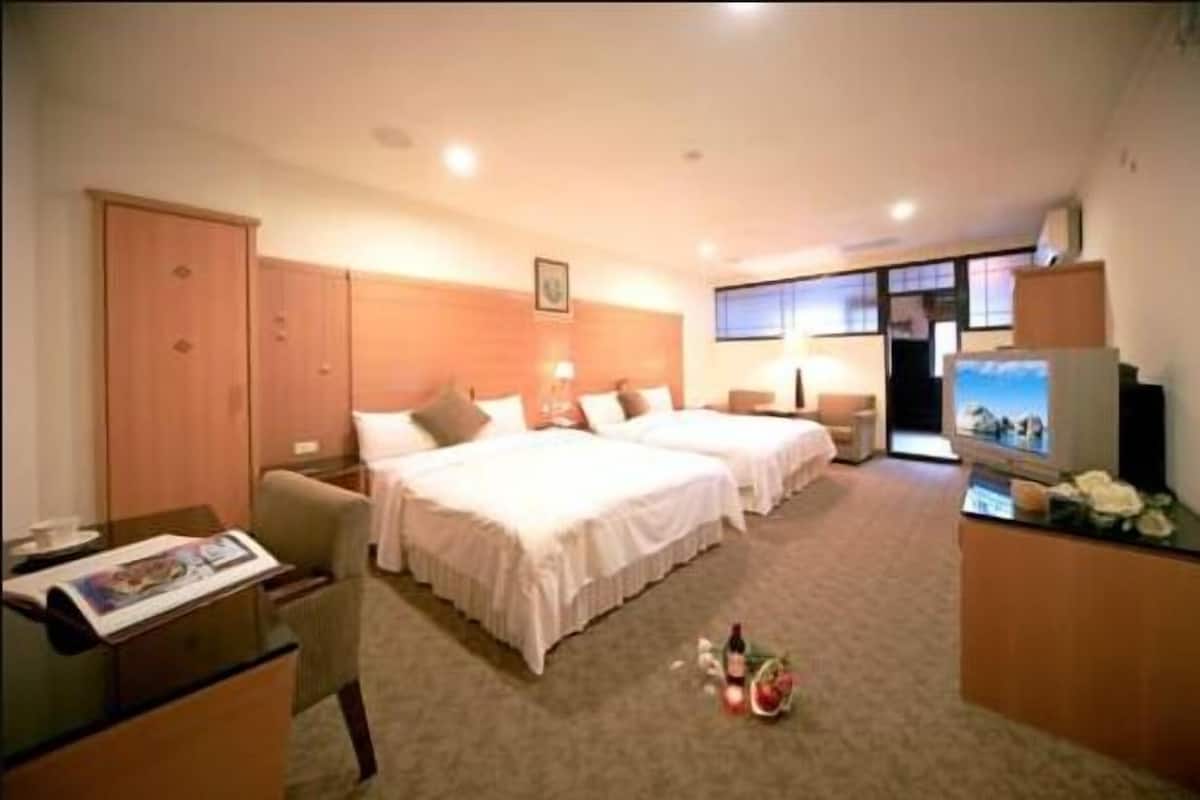 A hotel room with two beds, a desk, a TV, and a wardrobe.