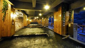 A hot spring bath area with wooden walls and a stone wall in the background. - Ming Lu Holiday Hotel (Ren'ai)