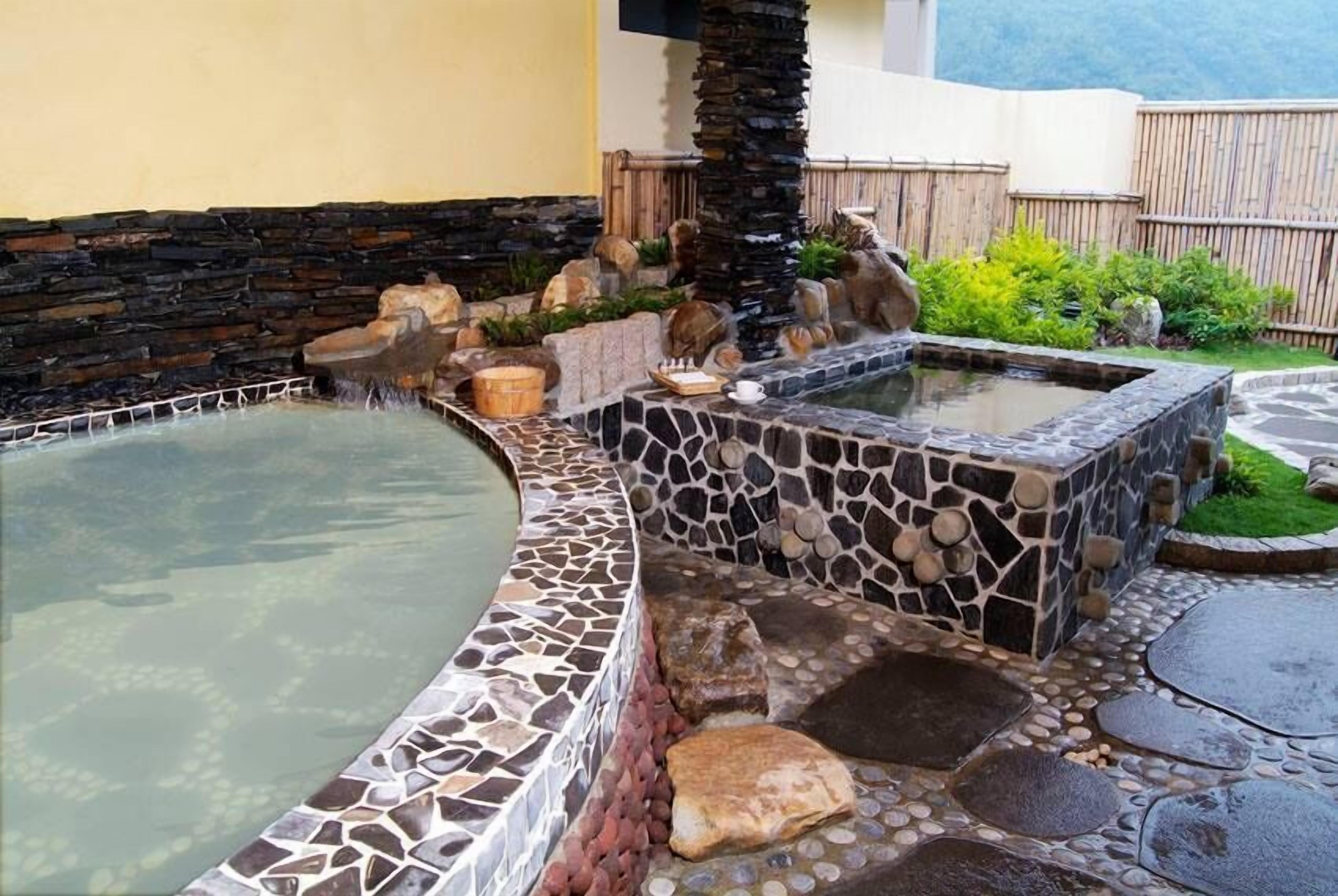 A spa area with a hot tub, stone walls, and a wooden fence.