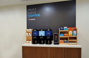 A coffee station with multiple coffee dispensers, a hot water dispenser, and a sign that reads 'MUST. HAVE. COFFEE.' - Holiday Inn Express & Suites Houston North I-45 Spring by IHG (Houston)