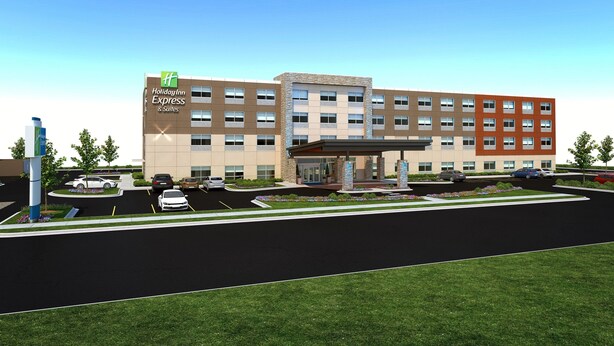 Un bâtiment Holiday Inn Express & Suites doté d’un parking, d’une entrée couverte et d’un espace paysager agrémenté de fleurs.