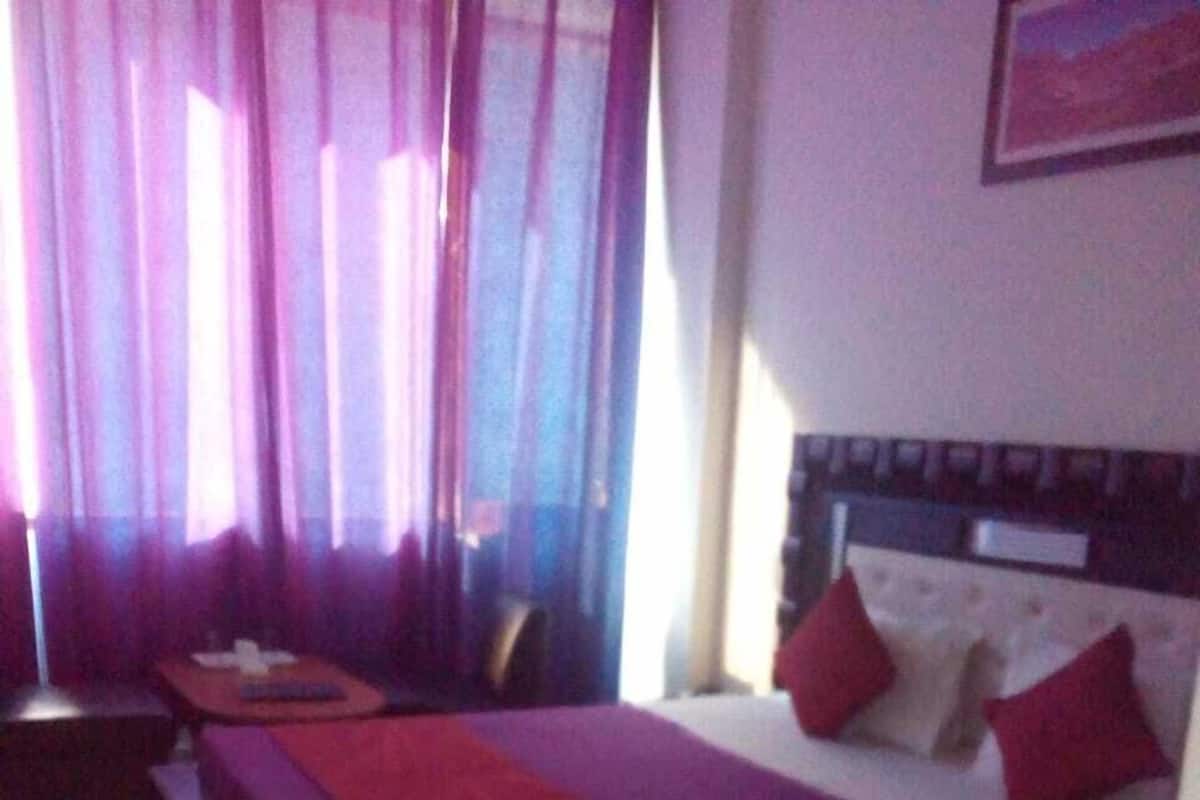 A hotel room with a large bed, a nightstand, and a chair.