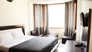 Habitació d'hotel amb un llit gran, una taula, una cadira i una televisió.