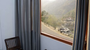 Vista per la finestra d'un paisatge muntanyós amb carretera i un camió.