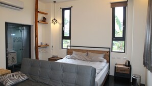 A bedroom with a bed, a bedside table, a nightstand, a sofa, a hanging light, and a window. - Morning Homestay (Puli)
