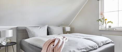 Ein Schlafzimmer mit einem großen Bett, einem Nachttisch mit Lampe, einem Fenster mit Aussicht und einer Deckenleuchte.
