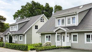 A row of two-story houses with grey siding and pitched roofs, featuring multiple windows and a well-maintained front yard. - Schwedenglück Prerow (Ostseebad Prerow)