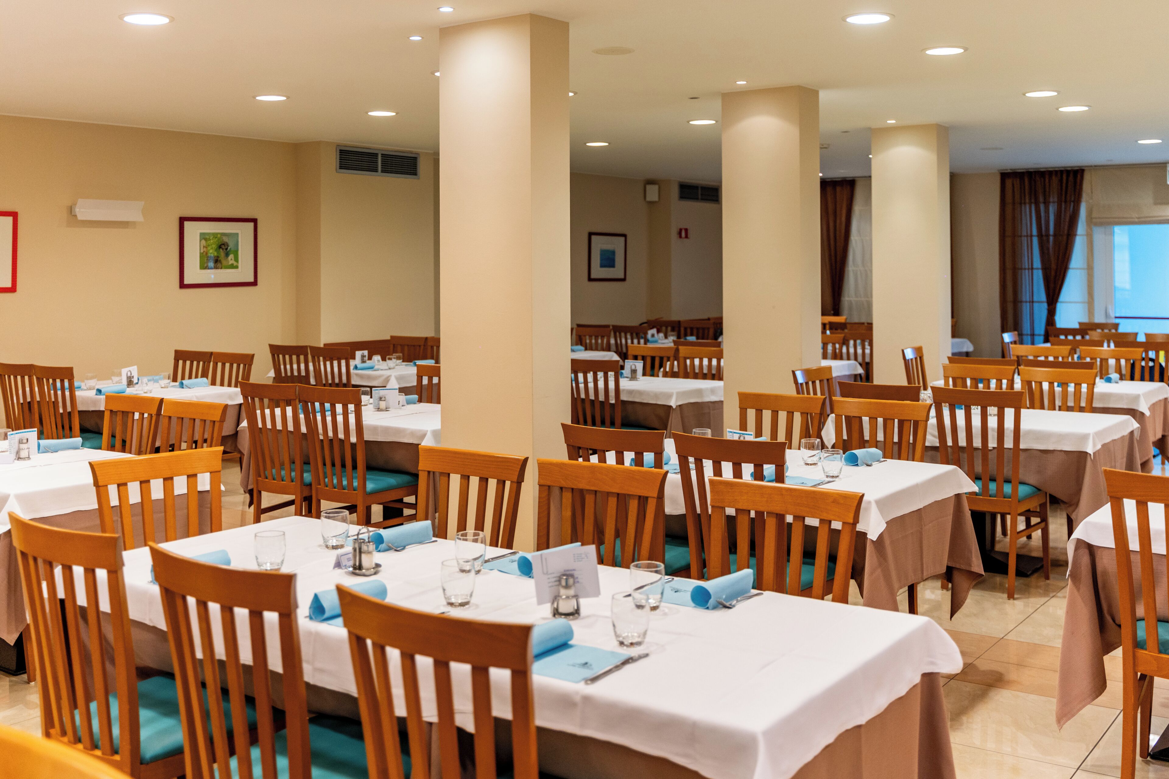A dining area with multiple tables and chairs, arranged in rows.