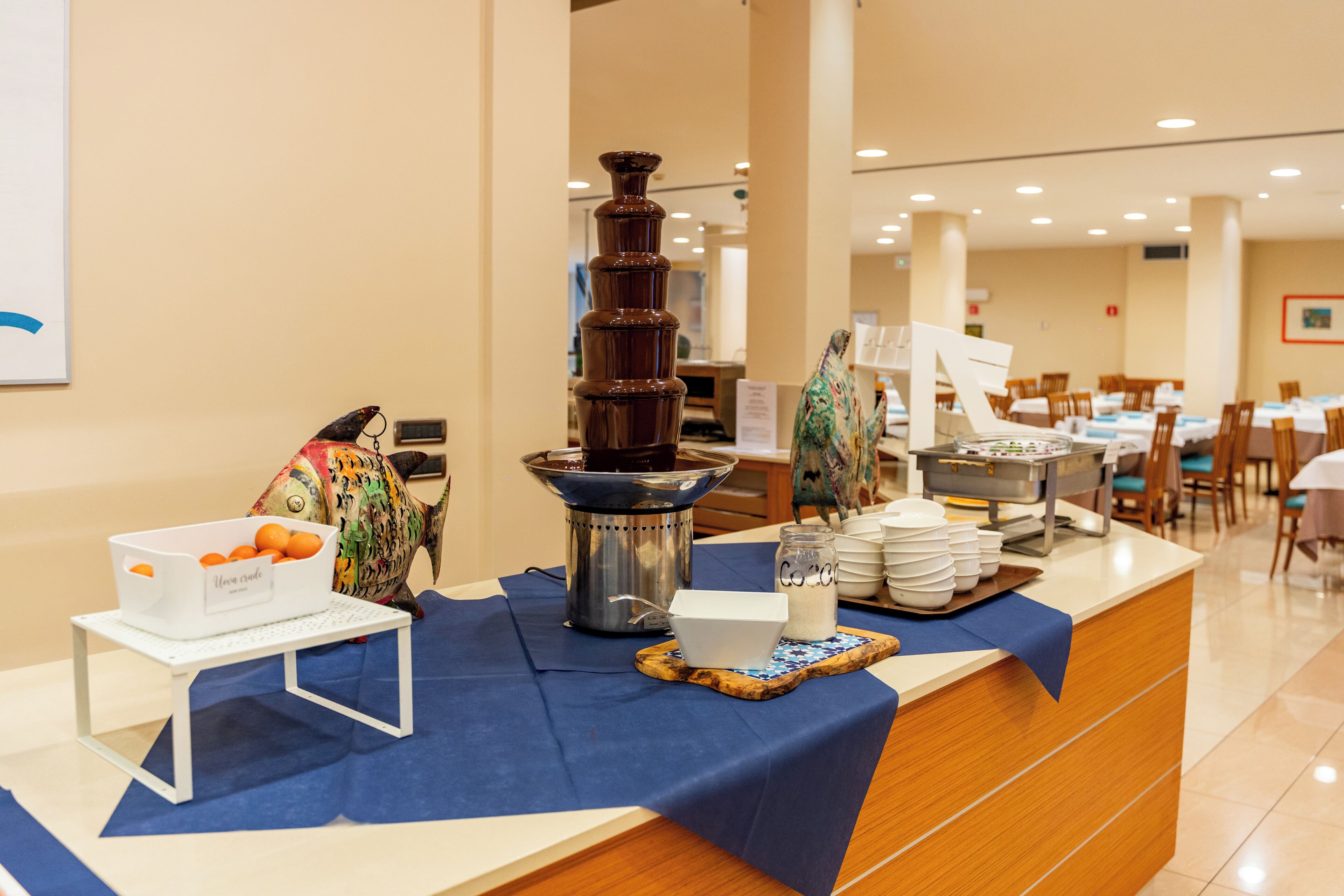 A buffet setup with a coffee urn, bowls, and plates.