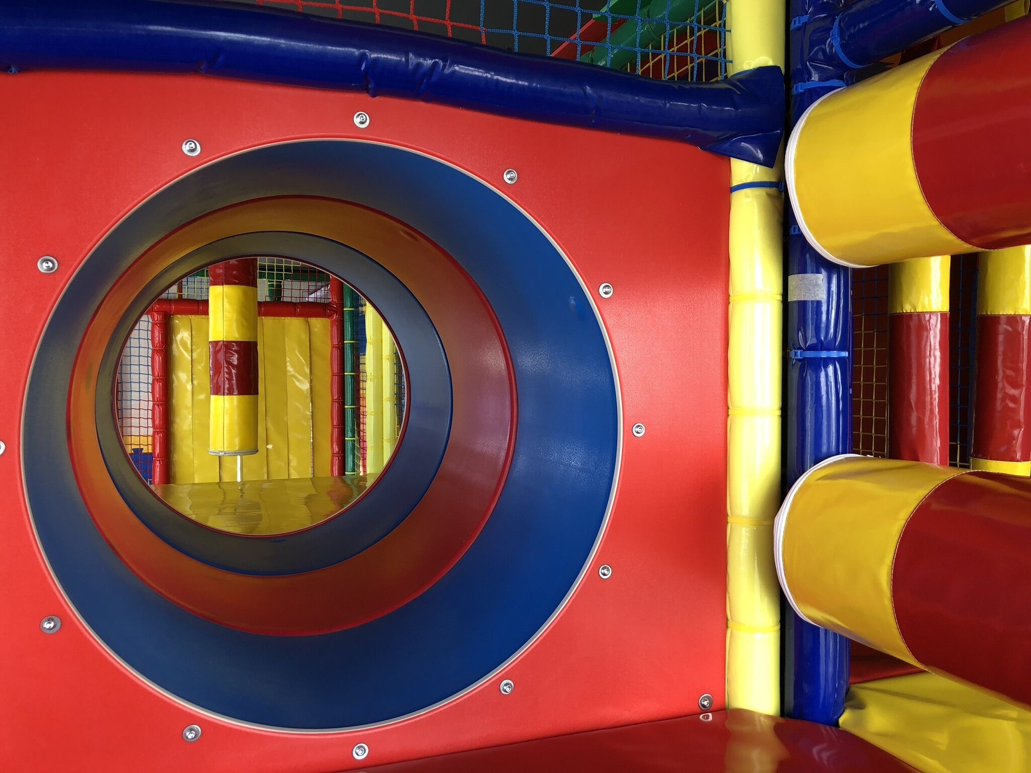 A circular play area with a blue and red exterior, surrounded by yellow and red padded walls.