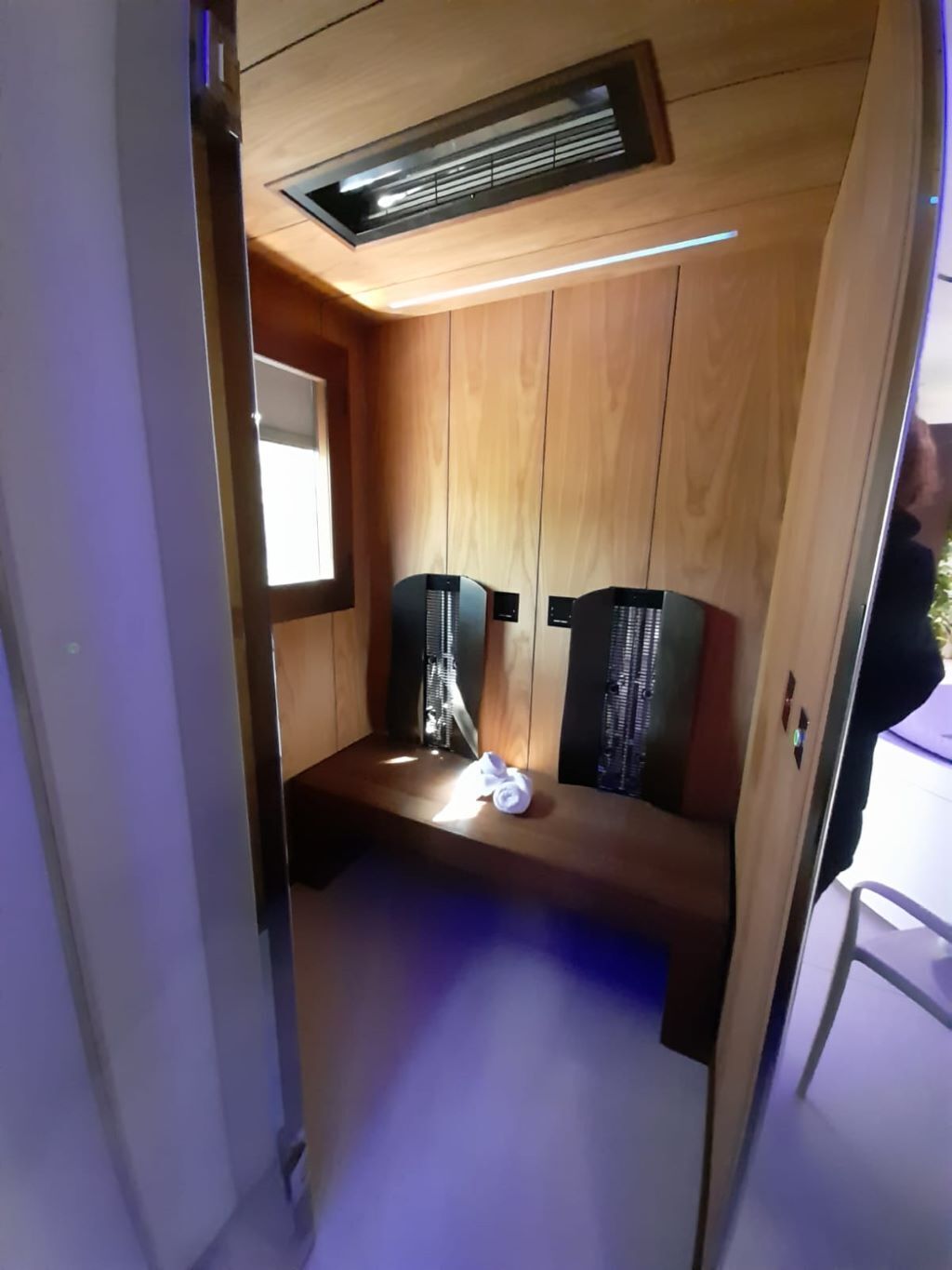 A compact room with wooden paneling, a small window, and a ceiling vent.