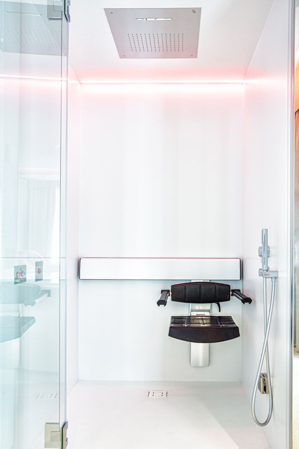 A modern bathroom with a glass shower enclosure, a wall-mounted sink, and a handheld showerhead.