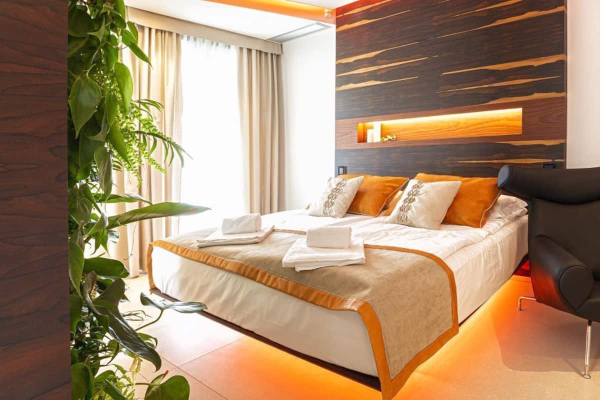 Une chambre d’hôtel moderne avec un grand lit, un mur décoratif en bois et une plante en pot.