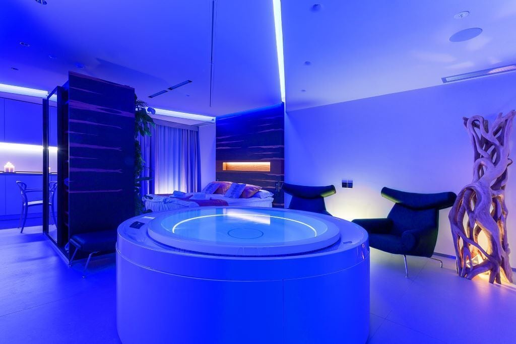 Una habitación moderna con una zona de estar circular, un sofá con cojines y una escultura de madera.