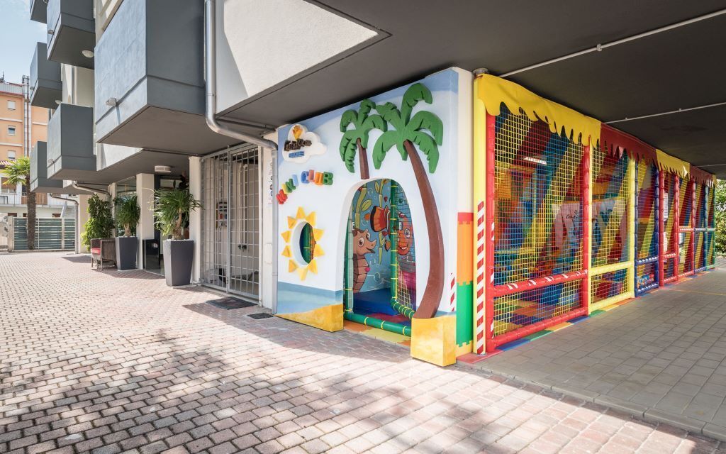 A children's play area with colorful murals and a netted climbing structure.